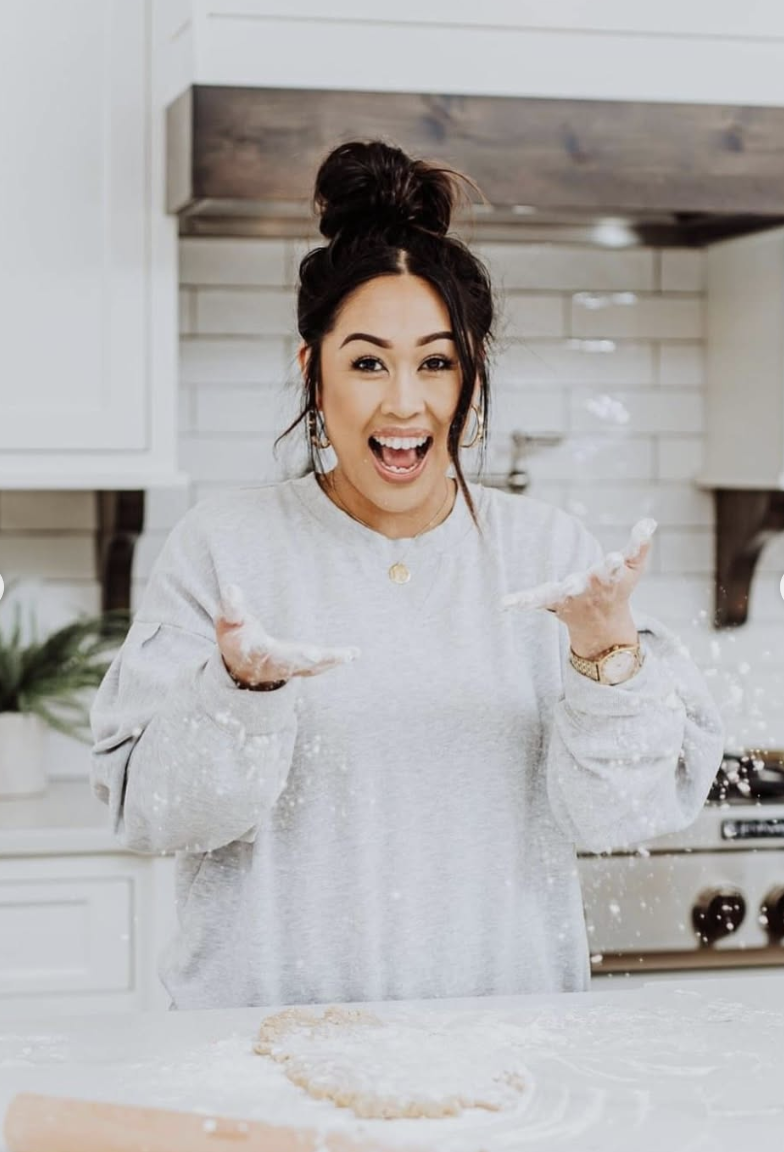 Vickie, owner of Slick's Sweets, laughing in her kitchen with flour in the air