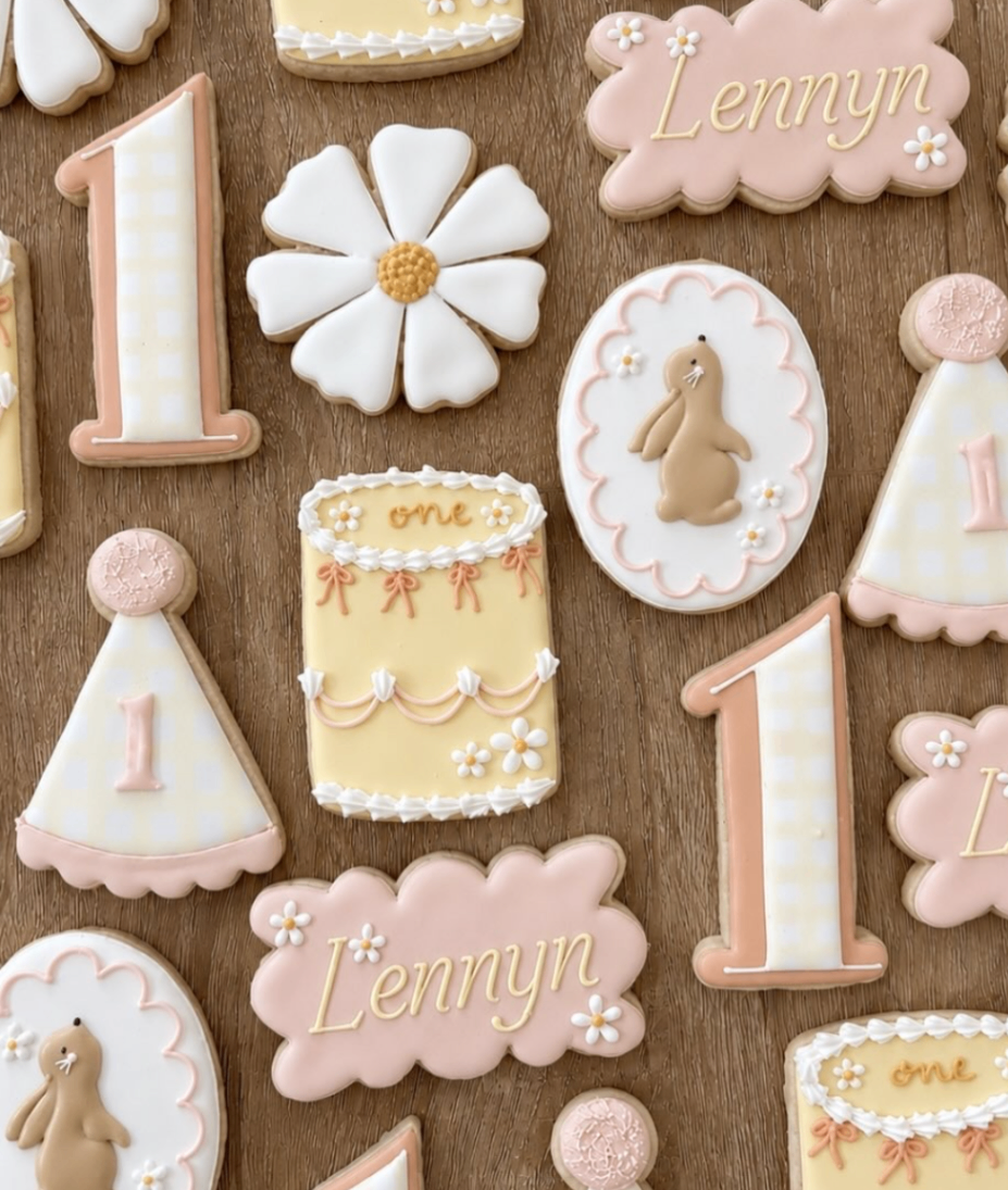 First birthday cookie set with pink scalloped name plaques, daisies, bunny motif, and number one cookies