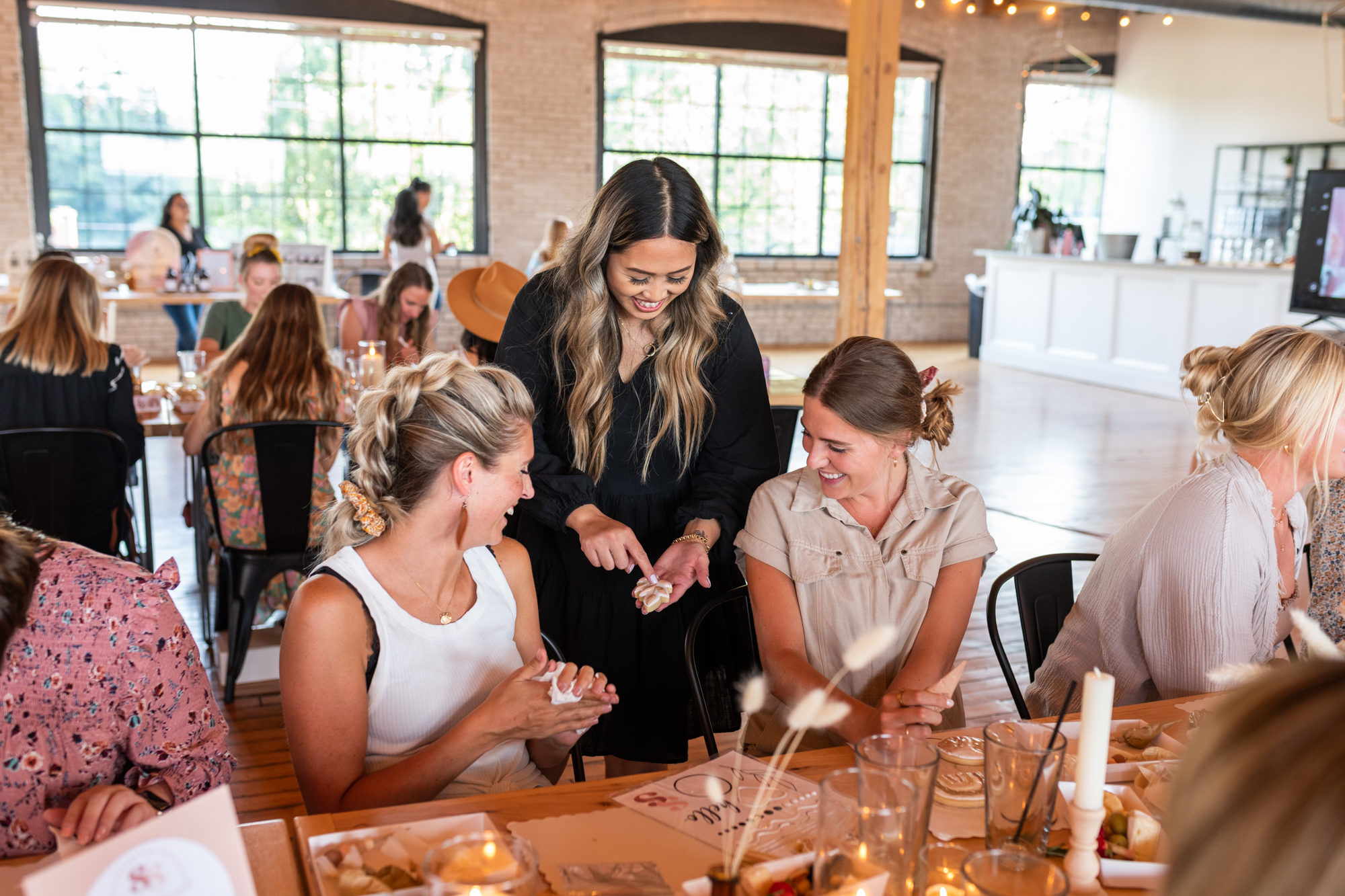 Vickie guiding guests through a cookie decorating class at a sunlit venue