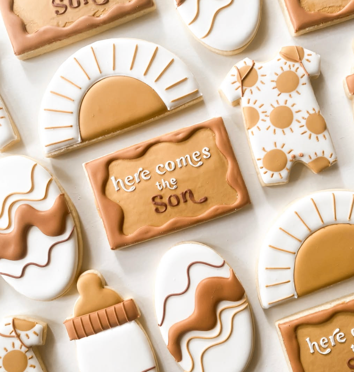 Warm sunshine themed cookie set with sunbursts, baby bottle, and wavy abstract details