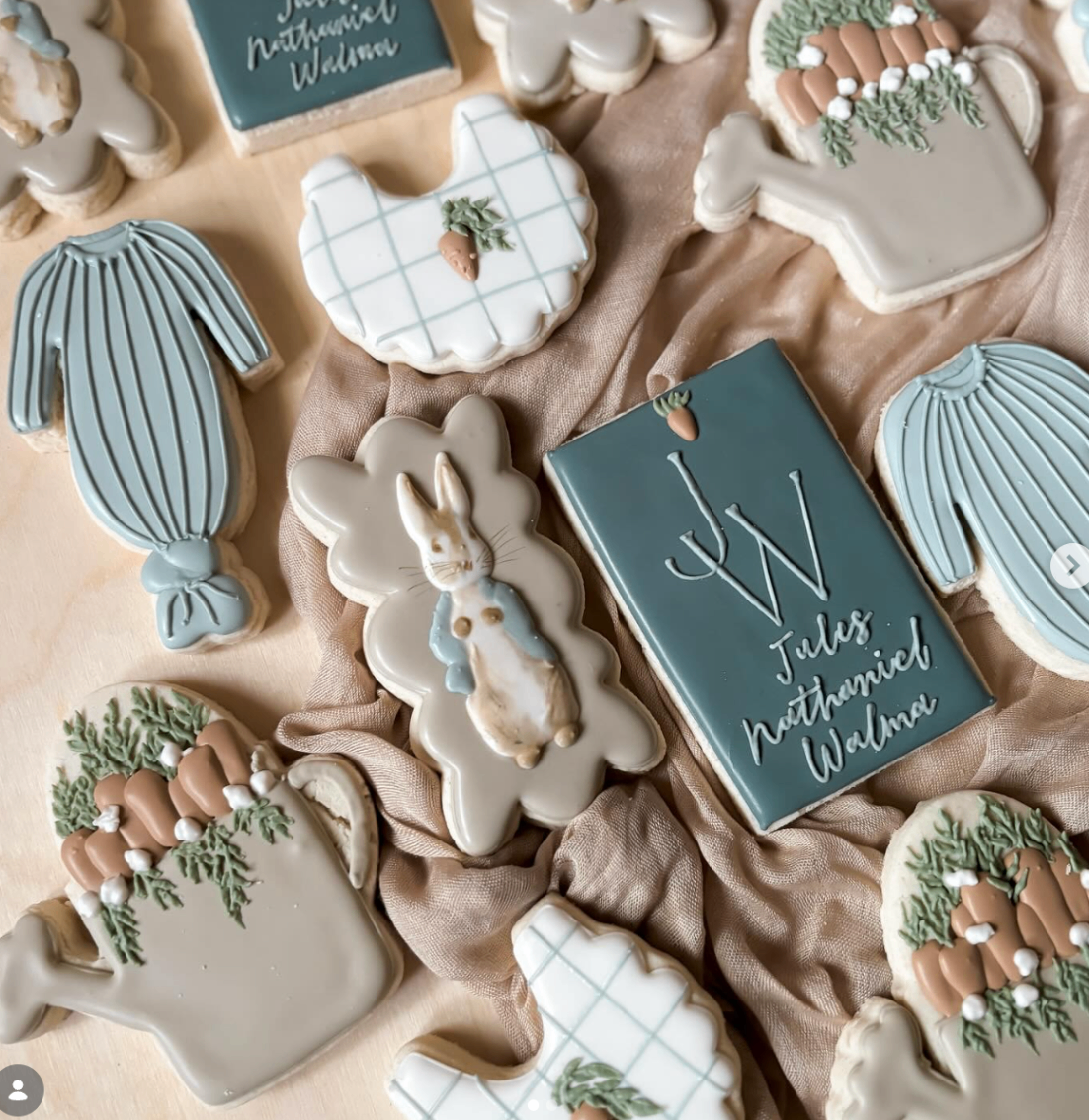 Soft blue and neutral bunny baby shower cookies with carrot and knit onesie details