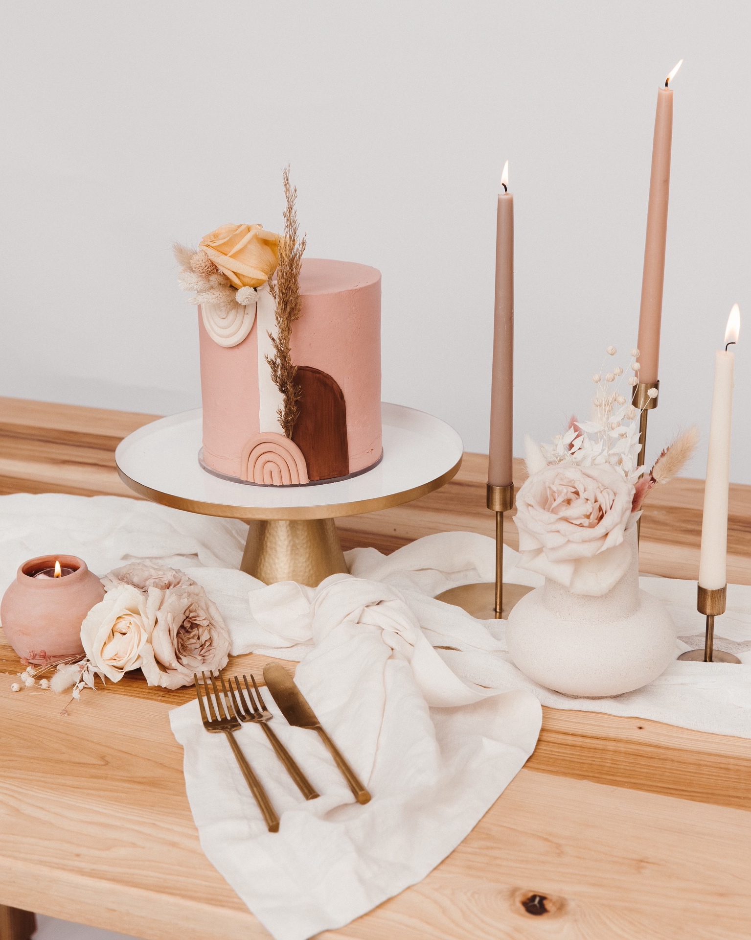 Pink boho cake styled on a tablescape with candles and roses