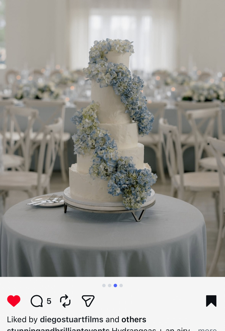 Four-tier white wedding cake with cascading blue hydrangeas